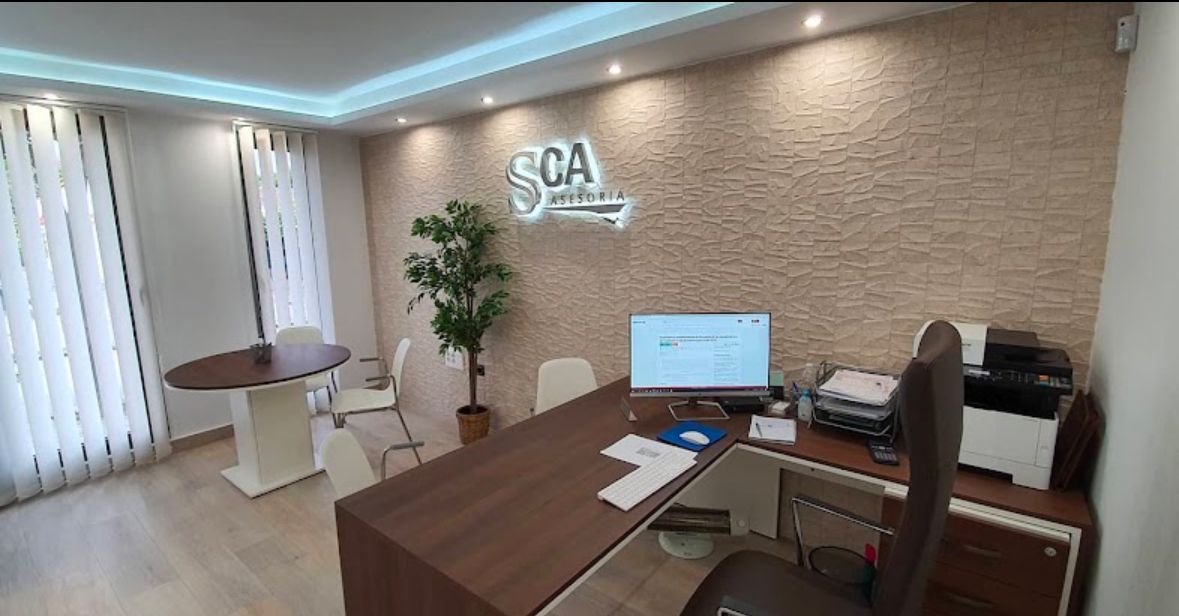 Interior del despacho de Asesoría SCA en Estella del Marqués: mesa de reuniones, escritorio y paredes con acabado de piedra cálida