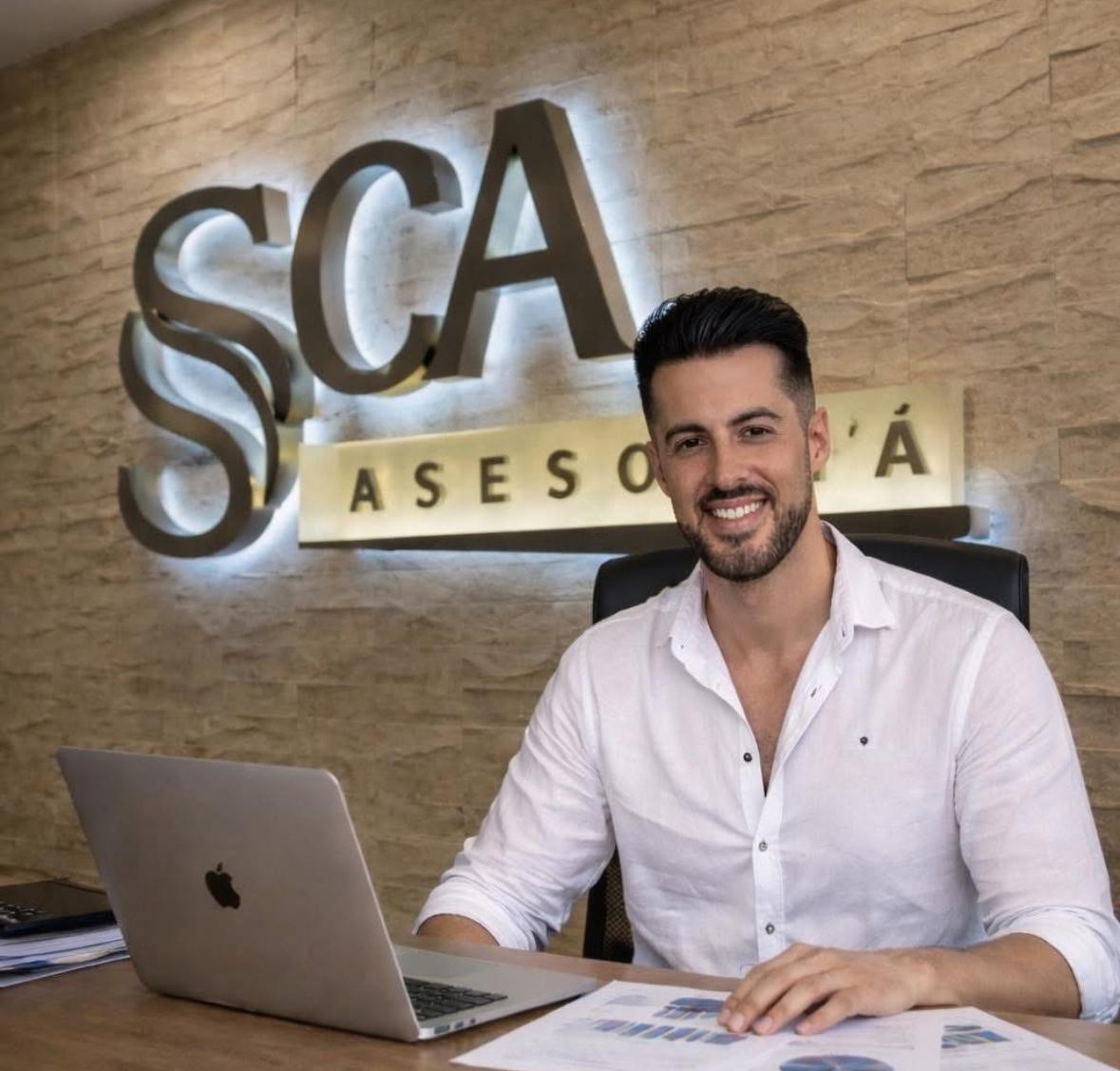 Sebastián, gerente y asesor titular de Asesoría SCA, sonriendo en su despacho de Estella del Marqués con el logo SCA retroiluminado al fondo